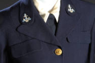 Detail view of uniform suit showing embroidered anchors on lapels and top brass button