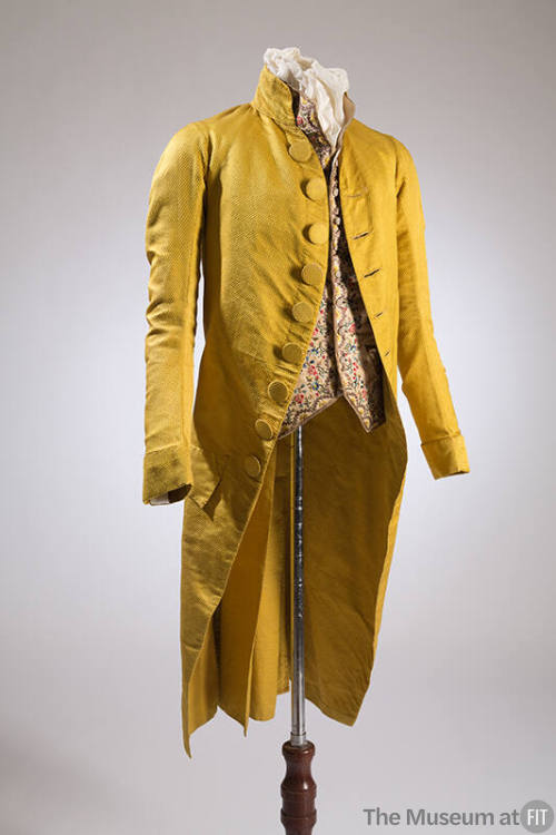Man’s yellow/green cutaway jacket with stand collar and large self-covered buttons dressed with…