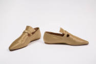 Pair of gold metallic flat shoes with pointed toe and strap over high, flared vamp tab