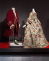 Installation image of platform with man’s red waistcoat, floral robe a la francaise and green L…