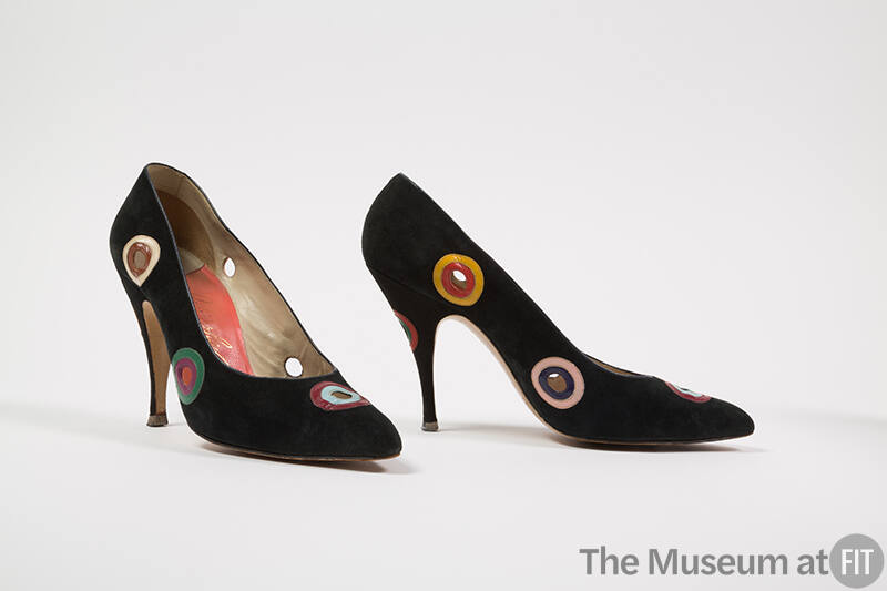 Pair of black high heel pumps with circular cut-outs throughout surrounded by concentric circle…