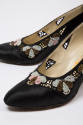 Detail of black pumps with cutouts and beaded floral design trim