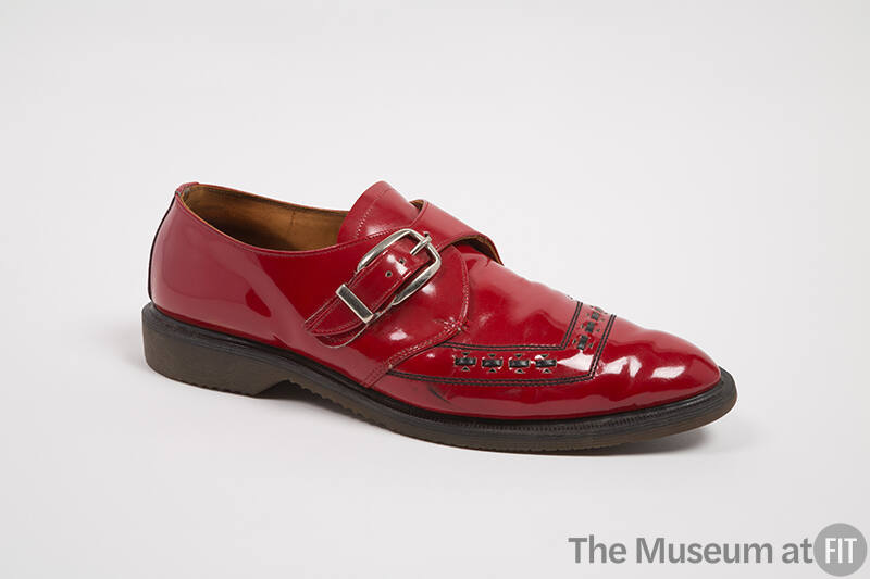 Red patent leather shoe with silver buckle strap and black stitched trim