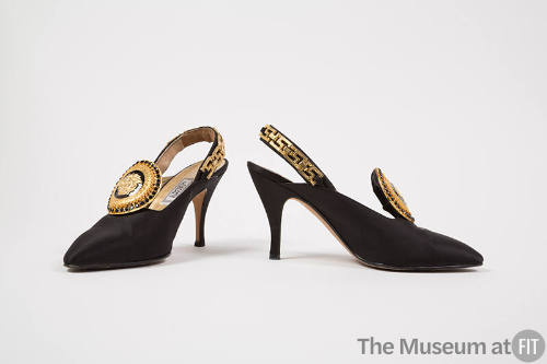 Pair of black slingback pumps with large black and gold Medusa head ornament on vamp, gold meta…