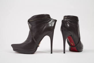 Dark grey leather stiletto heel pointy toe ankle boots with metal chain draped around instep