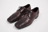 Man's dark red/brown lace up shoes with topstitched design of scrolling lines, swriling clouds,…