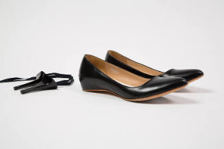Pair of black flat shoes pictured with necklace made of shoe lace and two black high heels