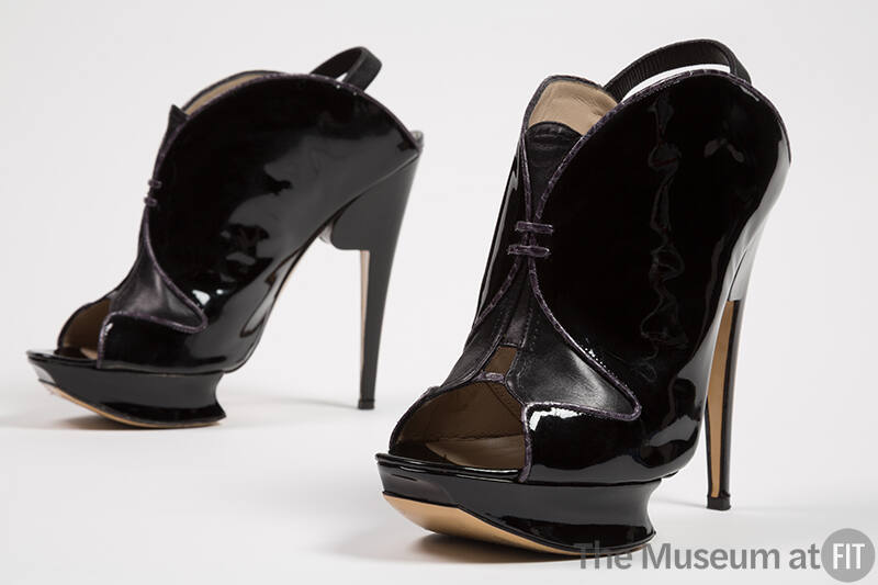 Pair of black patent leather open toe shoes with wedge platform, shaped stiletto heel, ankle st…