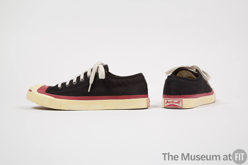 Pair of black sneakers with red trim around white sole and toe cap and red “Jack Purcell” writi…