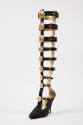 View of single black gladiator boot with buckle strap closures extending upwards from vamp and …