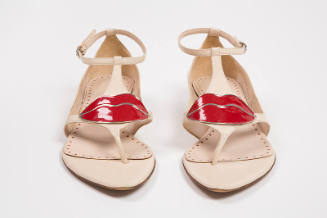 Beige thong sandals with enamel red lip ornament at t-strap, ankle straps