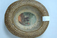 Interior view of straw hat with illustration of woman on horse and man on a high bicycle 