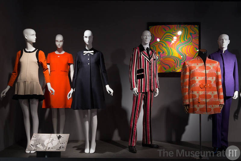 Trendology_33 Left to right 2012.27.1 (dress), 90.163.3 (orange dress), 85.151.5 (dress), 2001.55.1 (striped suit), 81.211.47 (textile wall), 2008.15.1 (jacket), 84.79.1 (suit) 