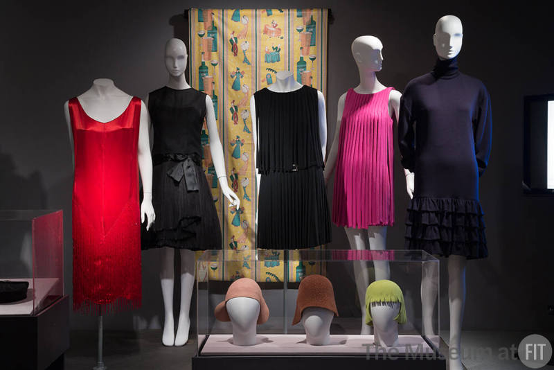 RetroSpective_06 Left to right 96.69.20 (dress), 86.106.6 (black dress),92.94.1 (textile wall), 70.43.21 (dress and belt), 90.8.1 (pink dress), 90.150.1 (blue dress), 77.178.10 and 81.23.46 and 91.178.1 (hats case)