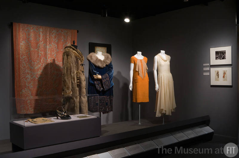 Eco-Fashion_30 Left to right 74.42.23 (bag case), 91.120.6 (shoes case), 80.93.7 (bag case), P87.39.1 (textile wall), P88.78.1 (fur coat), 2002.78.1 (coat), X428 (textile wall), 80.50.2 (orange dress), P83.39.7 (dress)