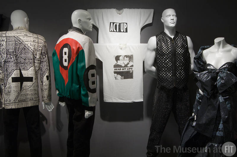 Fashion and Politics_53 Left to right 91.111.36 (jacket), 91.192.1 (leather jacket), 90.179.1 (t shirt wall), 90.179.2 (t shirt wall), 2005.40.4 and 2005.40.5 (vest and pants), 95.9.2 (dress)
