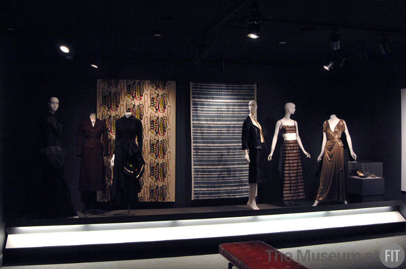 Arbiters_05 Left to right  76.196.31 (cape), 87.70.1 (suit), P84.17.5 (black dress), 96.121.3 (textile wall), 2002.45.1 (textile wall), 90.97.3 (suit), 2007.46.61 (bra and skirt), 2008.34.2 (metallic dress), 89.164.133, 89.164.130 and 75.230.104 (shoes case)