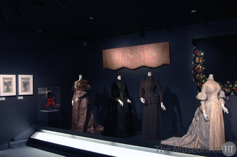 Arbiters_39 Left to right P85.35.19 (hat case), 73.40.1 (dress), 75.109.65 (textile wall), 2008.46.1 (velvet dress), 73.40.5 (suit), 92.100.1 (textile wall), P87.20.38 (two tone dress)