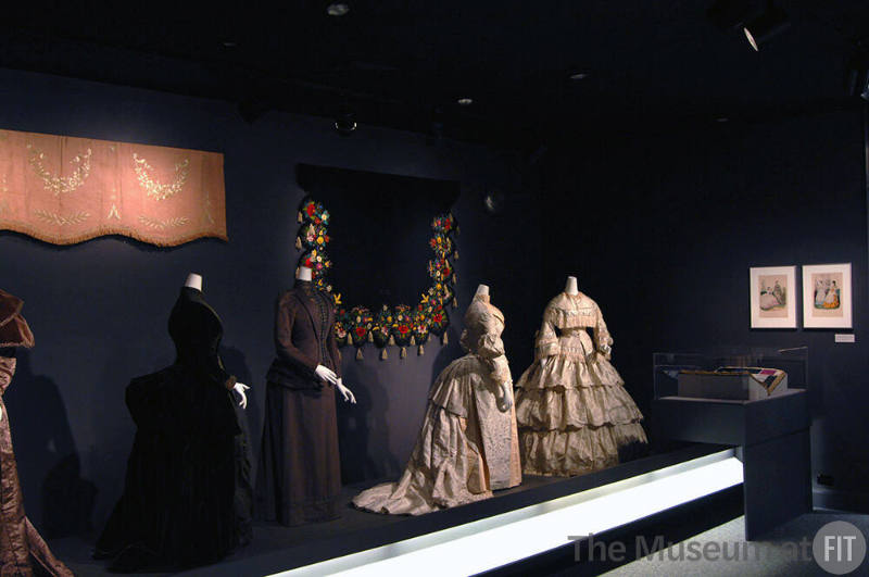 Arbiters_40 Left to right 75.109.65 (textile wall), 2008.46.1 (velvet dress), 73.40.5 (suit), 92.100.1 (textile wall), P87.20.38 (two tone dress), U.406 (tiered skirt dress), 79.153.17A (book case)