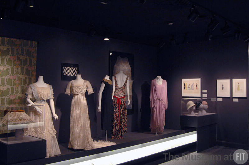 Arbiters_58 Left to right P83.19.12 (hat case), P92.34.6 (textile wall), 95.145.13 (lace and satin dress), 95.145.10 (wedding dress), X321.7A (textile wall), P91.76.1 (black dress), 71.268.7 (floral dress), P89.25.1A & F (textile wall), 84.201.1 (pink dress), P83.39.14, P83.39.16, 77.178.10 (hats case)