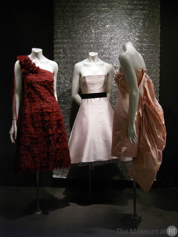 Rainbow_83 Left to right 2004.17.1 (layered dress), 2006.49.1 (white dress), 2004.50.1 (pink dress), 98.142.1 (textile wall)