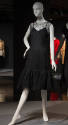 Sleeveless black net lace dress with round neck and scalloped hem ruffle over black slip 