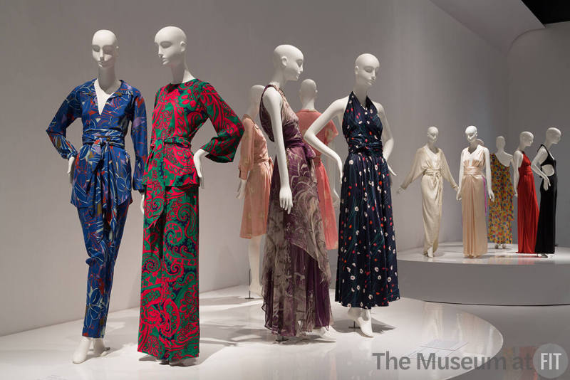 YSL+Halston_13 Left to right 91.41.12 (blue ensemble), P89.55.4 (paisley ensemble), 86.126.14 (purple grey dress),  91.41.1 (floral dress), 91.104.1 (white dress), 91.235.4 (halter dress), 87.146.27 (floral dress), 88.1.69 (orange dress), 79.66.40 (black jumpsuit)