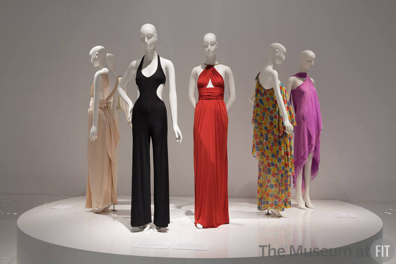 YSL+Halston_20 Left to right 91.104.1 (white dress hidden), 91.235.4 (halter dress),  79.66.40 (black jumpsuit), 88.1.69 (orange dress), 87.146.27 (floral dress), 82.3.5 (purple dress)