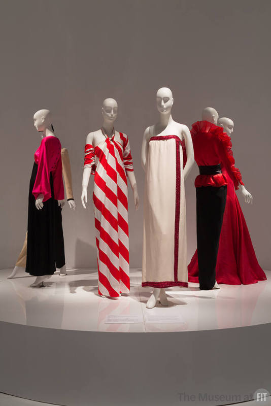 YSL+Halston_39 Left to right 82.99.1 (pink and black gown), 80.128.10 (red white stripe dress), 2014.38.2 (ivory evening dress), 2007.56.16 (ruffle top and black skirt),  91.185.2 (red strapless gown)