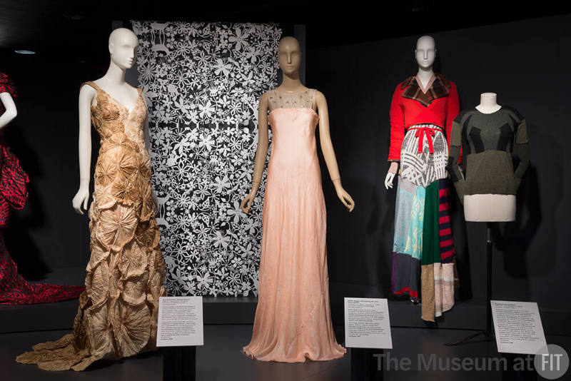 Exhibitionism_3 Left to right 2010.48.1 (gown), 2005.27.1 (textile wall), 2010.18.1 (pink dress), 95.7.1 (knit ensemble), 2008.80.1 (sweater)