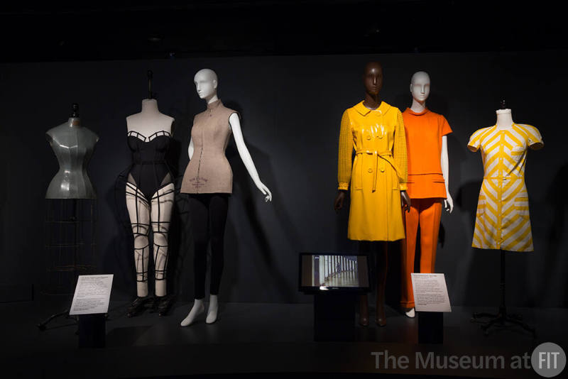 Exhibitionism_6 Left to right 2017.53.1 (black ensemble), 2008.91.1 (jacket), 77.21.4 (coat), 81.24.9 (orange pantsuit), 77.57.2 (dress)