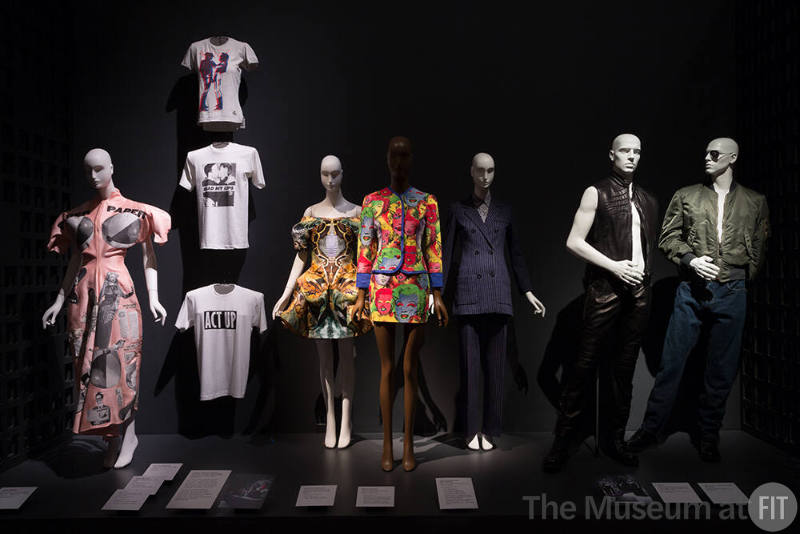 Exhibitionism_12 Left to right 89.102.2 (pink dress), 2001.44.4 (shirt wall top), 90.179.2 (shirt wall middle), 90.179.1 (shirt wall bottom), 2012.36.2 (printed dress), 2010.56.1 (skirt suit), 78.57.6 (blue pantsuit), 2008.28.1 and 2008.28.2 (leather vest and pants), 88.134.28 (jacket)