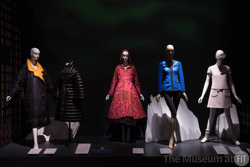 Exhibitionism_14 Left to right 2006.62.7 (yellow collar coat), 2016.80.1 (black coat), 2010.37.7 and 2010.37.8 (coat and skirt), 2017.9.1 (blue jacket), 2014.56.2 (glasses), 78.170.5 (dress), 77.183.2CD (boots) 