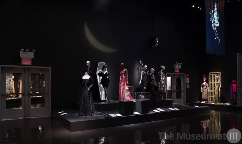 Exhibitionism_22 Left to right 2007.23.2 (beaded dress), 2007.2.1 (black ensemble hidden), 99.80.1 (velvet dress), 2008.55.1 (gown with red), 2008.5.1 (hat case), 2018.3.2 (earrings case), 2009.10.1 (ensemble with medical parts), 2010.94.1 (cape skirt suit), 2011.58.1 (silver ensemble)