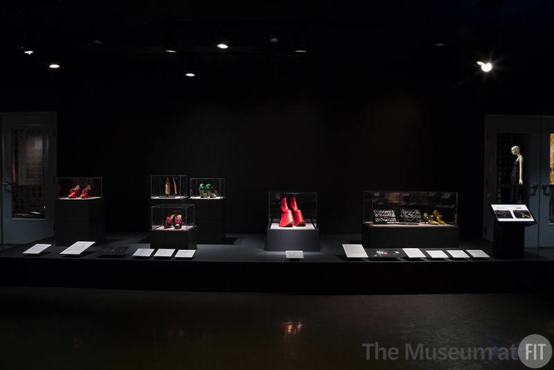 Exhibitionism_29 Left to right 99.3.1 (red shoes), 2012.38.1 (shoes front case), 2014.35.1 (ballet shoes), 2013.14.1 (green shoes), 2010.59.1 (boots), 78.57.67 (bag), 2014.41.1 (bag copy), 99.30.9 (shoe), 2014.43.1 (shoe copy) 