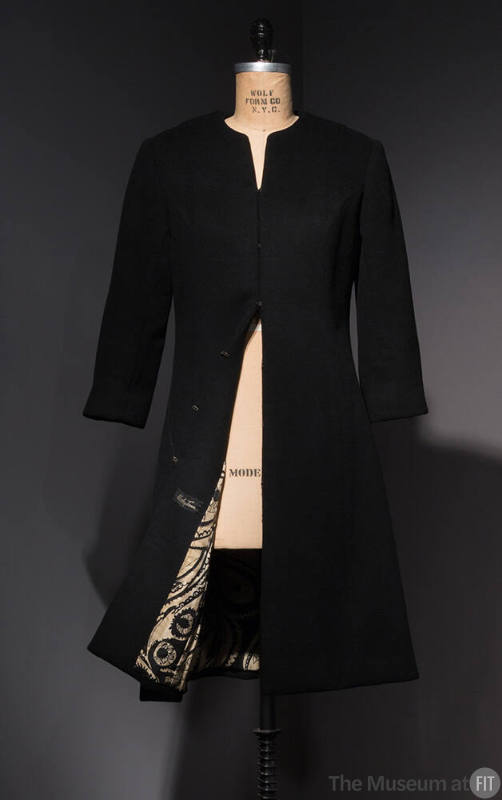 Black collarless coat with front hook and eye closures and bottom hem open to reveal black and …