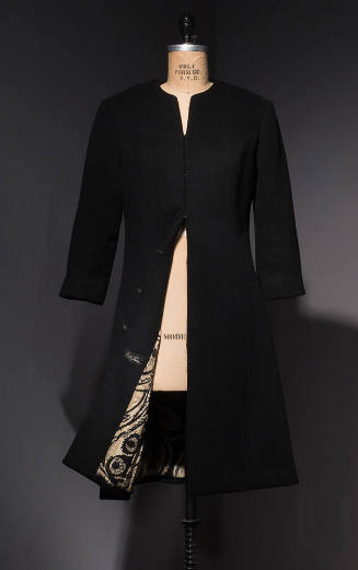 Black collarless coat with front hook and eye closures and bottom hem open to reveal black and …