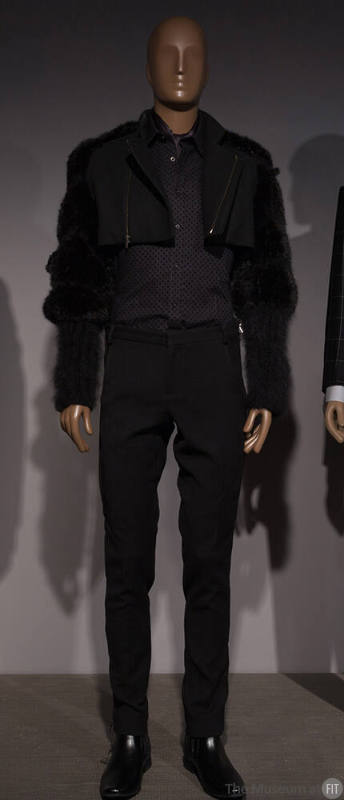 Man’s black ensemble of bolero jacket with fur sleeves, polka dot button front shirt, slim pant…