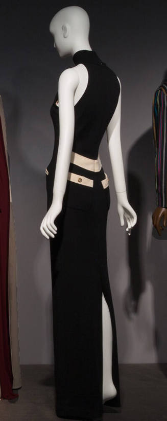 Back view of sleeveless floor length black dress with off-white waist band and pocket flaps wit…