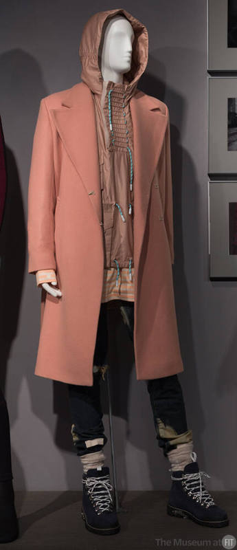Man’s beige notch collar coat, tan jacket with hood, blue distressed denim jeans and blue hikin…