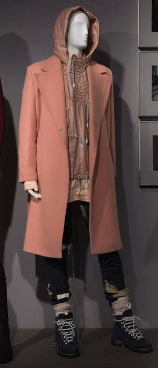 Man’s beige notch collar coat, tan jacket with hood, blue distressed denim jeans and blue hikin…