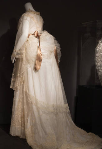Back view of sheer net bodice, apron and skirt with bustle and train, embroidery throughout and…