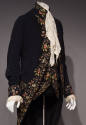 Alternate view of man’s navy blue floral embroidered coat and matching vest dressed with long w…