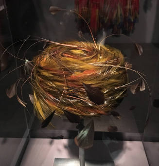 Small pillbox hat of wrapped green, black and brown feathers and projecting stripped quills