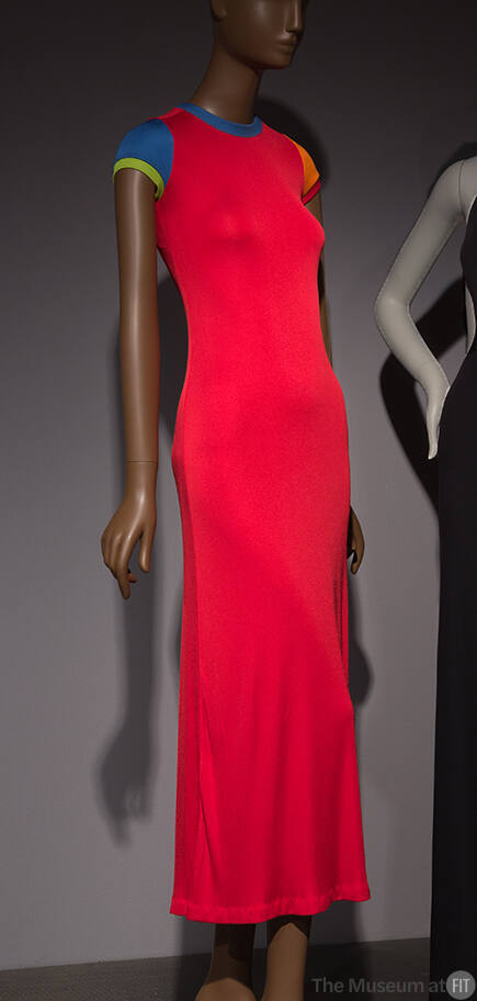 Long red dress with short sleeves, crew neck trimmed in blue, blue left sleeve and orange right…