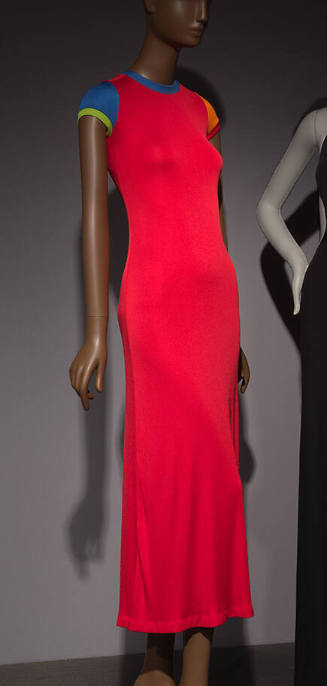 Long red dress with short sleeves, crew neck trimmed in blue, blue left sleeve and orange right…